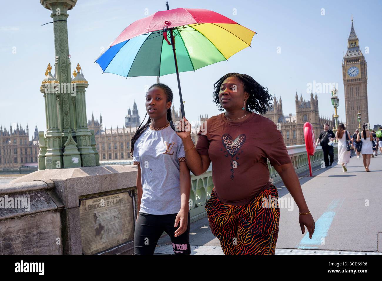Au début de la quatrième vague de chaleur estivale de 2025, lorsque le met Office prévoit un autre avertissement de santé publique pour des températures atteignant 34 degrés Celsius à Londres et dans le sud-est, des membres du public traversent Westminster Briidge, le 12 août 2025, à Londres, en Angleterre. Le Groupe national de lutte contre la sécheresse a également ajouté des avertissements à l'Angleterre pour faire face à des pénuries d'eau « importantes au niveau national ». Banque D'Images