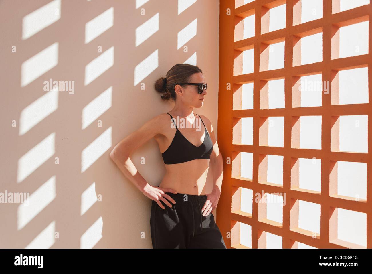 Femme sportive à la mode en lunettes de soleil avec architecture moderne et ombres Banque D'Images