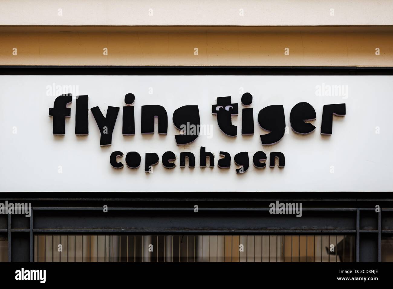 Un panneau noir et blanc avec le logo de la boutique 'Flying Tiger copenhagen' dessus, monté sur la façade d'un bâtiment. Banque D'Images