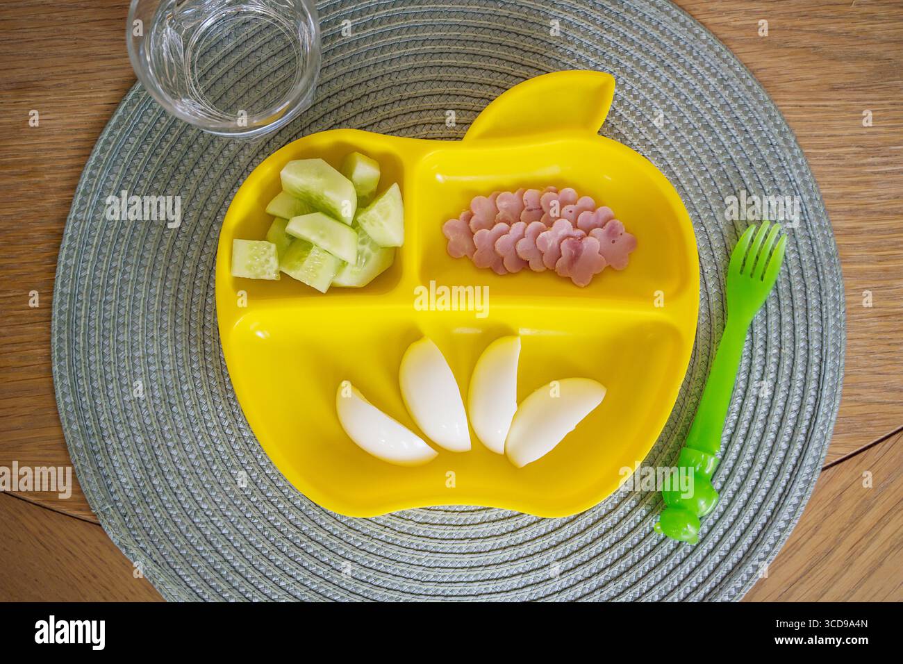 Nourriture pour enfants, mangeurs difficiles, œufs durs, jambon et concombre, assiette en plastique jaune Banque D'Images