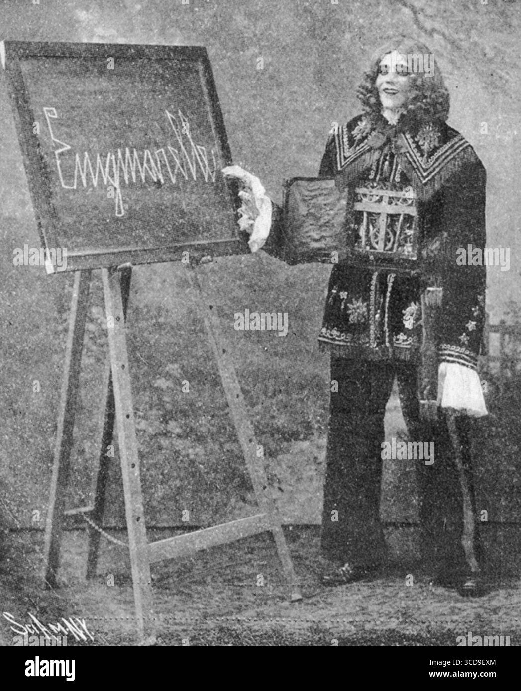 Enigmarelle, canular théâtral présenté comme un automate humanoïde mais opéré par une personne cachée, pose à côté d'un tableau noir lors d'une représentation. Exposée aux États-Unis et en Europe vers 1905, Enigmarelle est considérée comme une merveille scientifique et prétend réaliser des exploits tels que la marche, le vélo et l'écriture de son nom. Banque D'Images