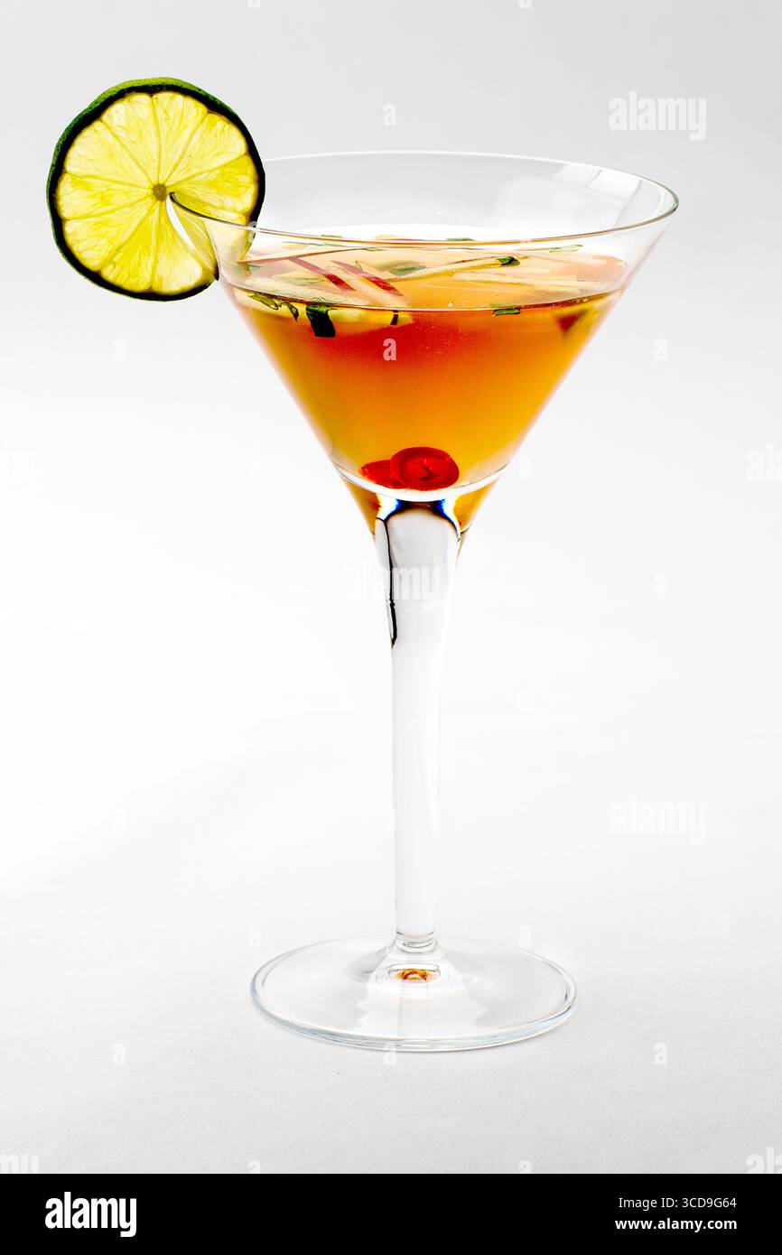 Cocktail rafraîchissant servi dans un verre à martini garni d'une rondelle de citron vert et d'une cerise, isolé sur fond blanc. Banque D'Images