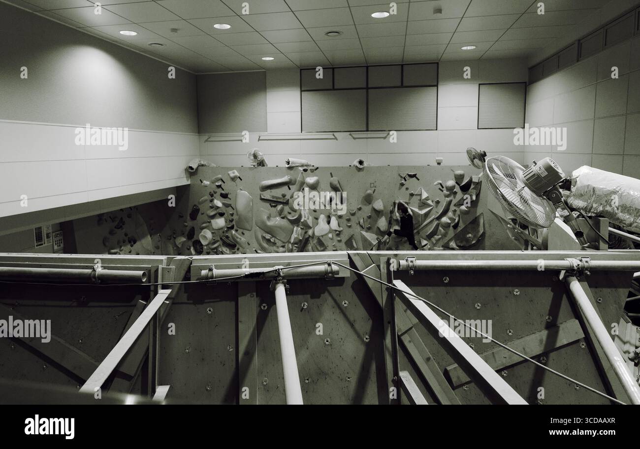 Vue en noir et blanc d'un mur de blocs intérieur avec un grimpeur s'attaquant à des prises difficiles Banque D'Images