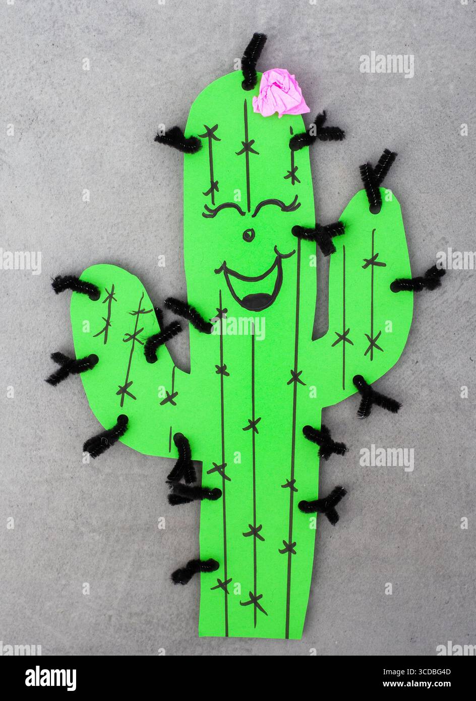 Cactus vert avec une fleur rose sur le dessus et pointes de nettoyeur de tuyaux noir et blanc. Le cactus est souriant et a une expression heureuse Banque D'Images