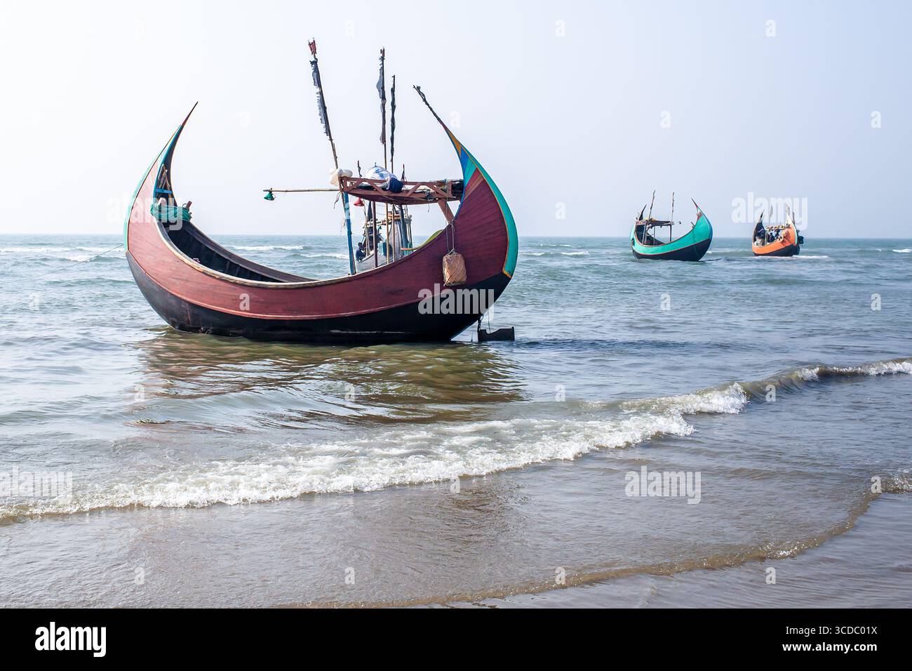 Cox's Bazar, Bangladesh - 04 février 2024 : vue des bateaux de pêche traditionnels reposant sur la rive sablonneuse, l'eau turquoise lançant doucement contre les coques. Banque D'Images