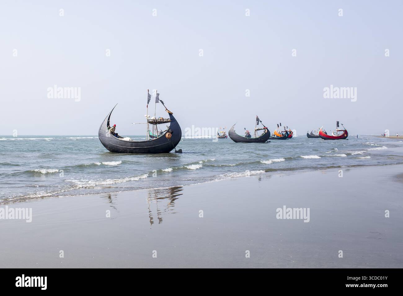 Cox's Bazar, Bangladesh - 04 février 2024 : vue de bateaux de pêche traditionnels qui bondissent doucement sur les eaux tranquilles et réfléchissantes de la baie du Bengale, sous un ciel serein. Banque D'Images