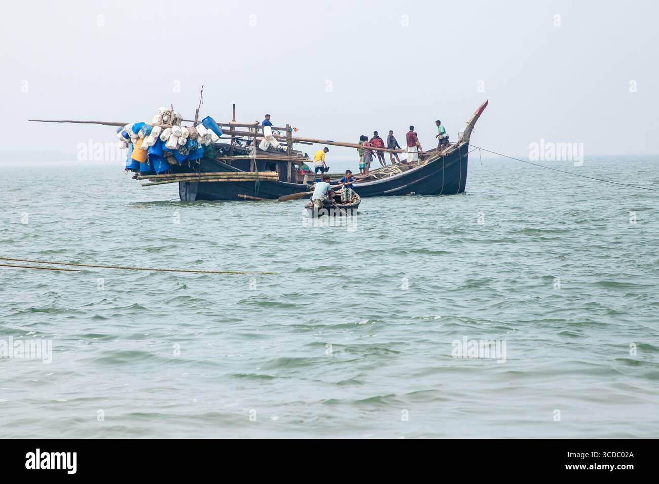 Cox's Bazar, Bangladesh - 07 février 2024 : vue d'un bateau de pêche traditionnel chargé de filets et de pêcheurs le long de l'autoroute Cox's Bazar - Teknaf, contre un horizon brumeux. Banque D'Images