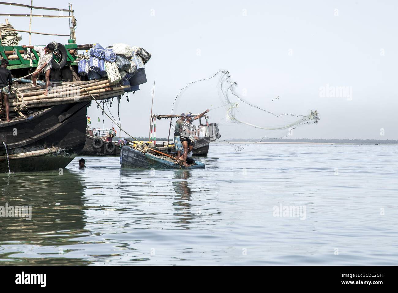 Cox's Bazar, Bangladesh - 29 novembre 2022 : vue de pêcheurs jetant des filets depuis leurs bateaux sur les eaux calmes et chatoyantes de la baie, sous un ciel clair et large. Banque D'Images