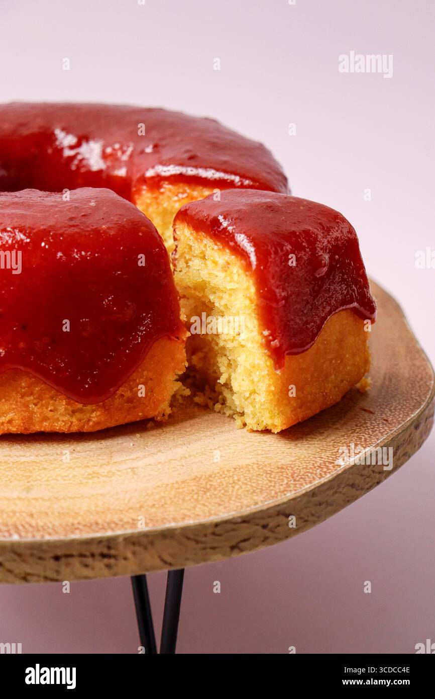 Tranche d'un gâteau éponge à la vanille avec garniture de coulis de fraise sur un support de gâteau en bois. Un morceau, tranche de gâteau est servi Banque D'Images