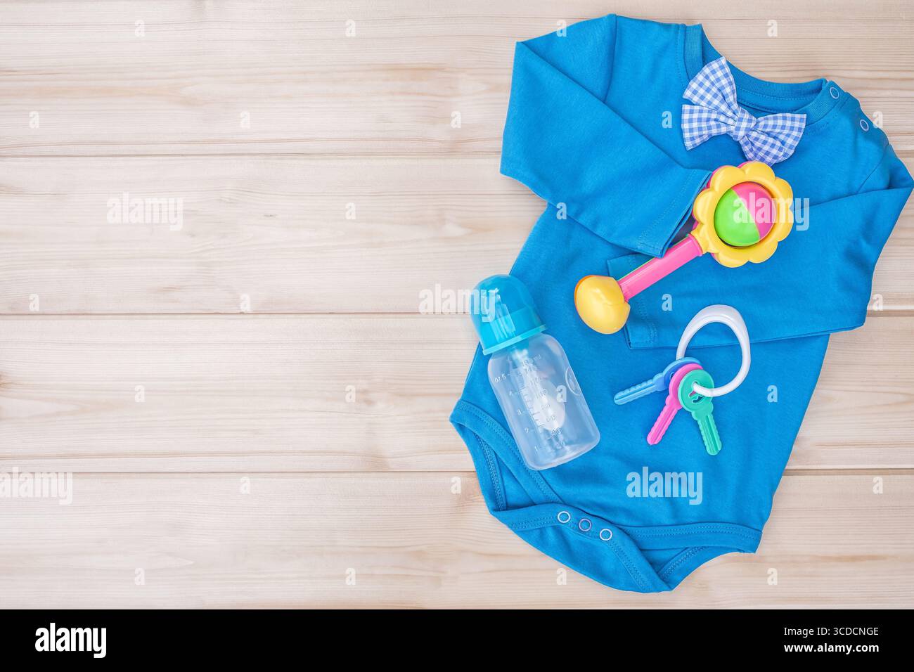 Body en coton bleu avec jouets pour bébé. Ensemble de vêtements de bébé garçon isolé sur fond de bois, vêtements d'enfant masculin. Vêtements pour nourrissons et hochet avec alimentation Banque D'Images
