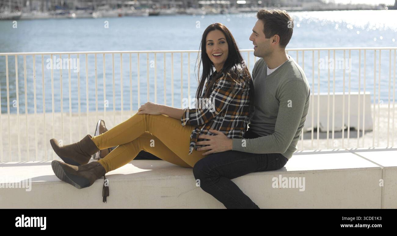 Loving couple au bord de l'assise dans une étreinte étroite sur un banc sur une promenade avec vue sur la mer Banque D'Images