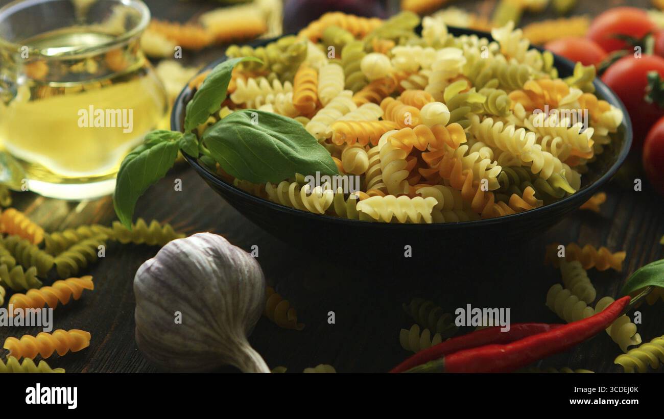 Big Black bowl full of macaroni aux légumes spirale colorée placée près de sur la table en bois Banque D'Images