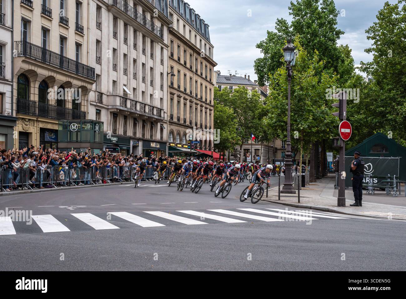 Peloton en course sur la place de la Madeleine lors de la dernière journée du Tour de France hommes 2025. La foule applaudit, applaudit et prend des photos Banque D'Images