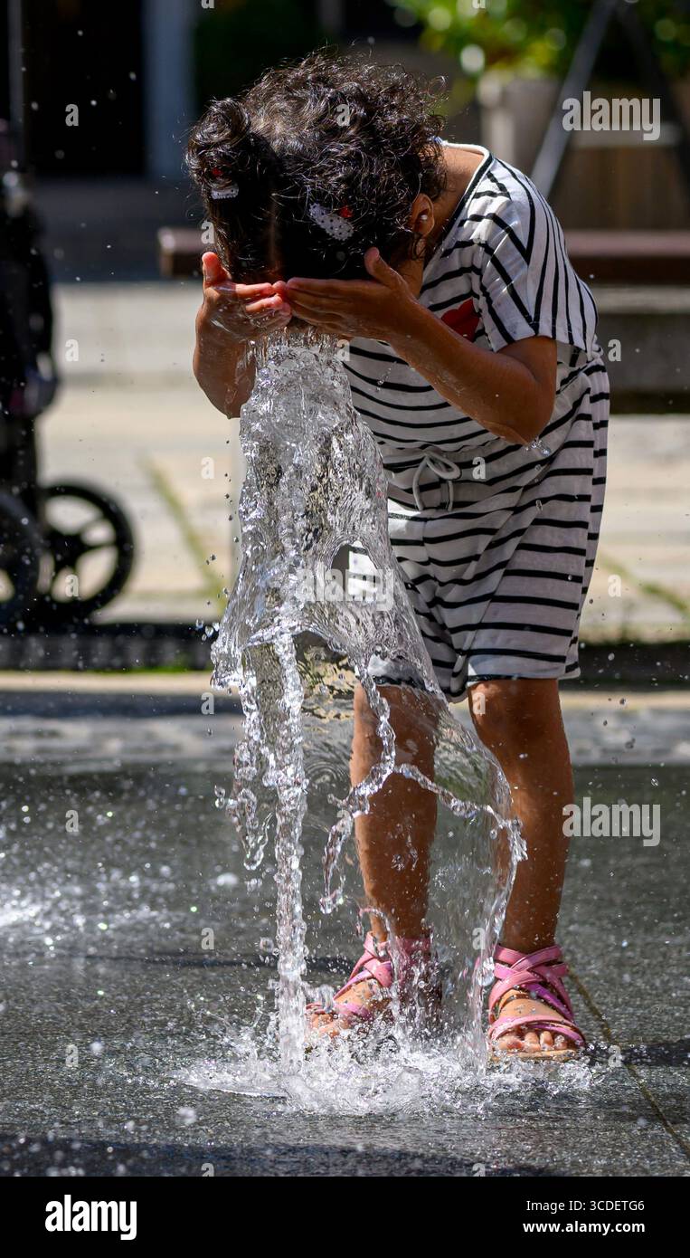 Chemnitz, Allemagne. 13 août 2025. Une petite fille se rafraîchit à une fontaine dans le centre de Chemnitz. À des températures d'environ 30 degrés Celsius, les caractéristiques de l'eau offrent un moyen bienvenu de se rafraîchir. Crédit : Hendrik Schmidt/dpa/Alamy Live News Banque D'Images