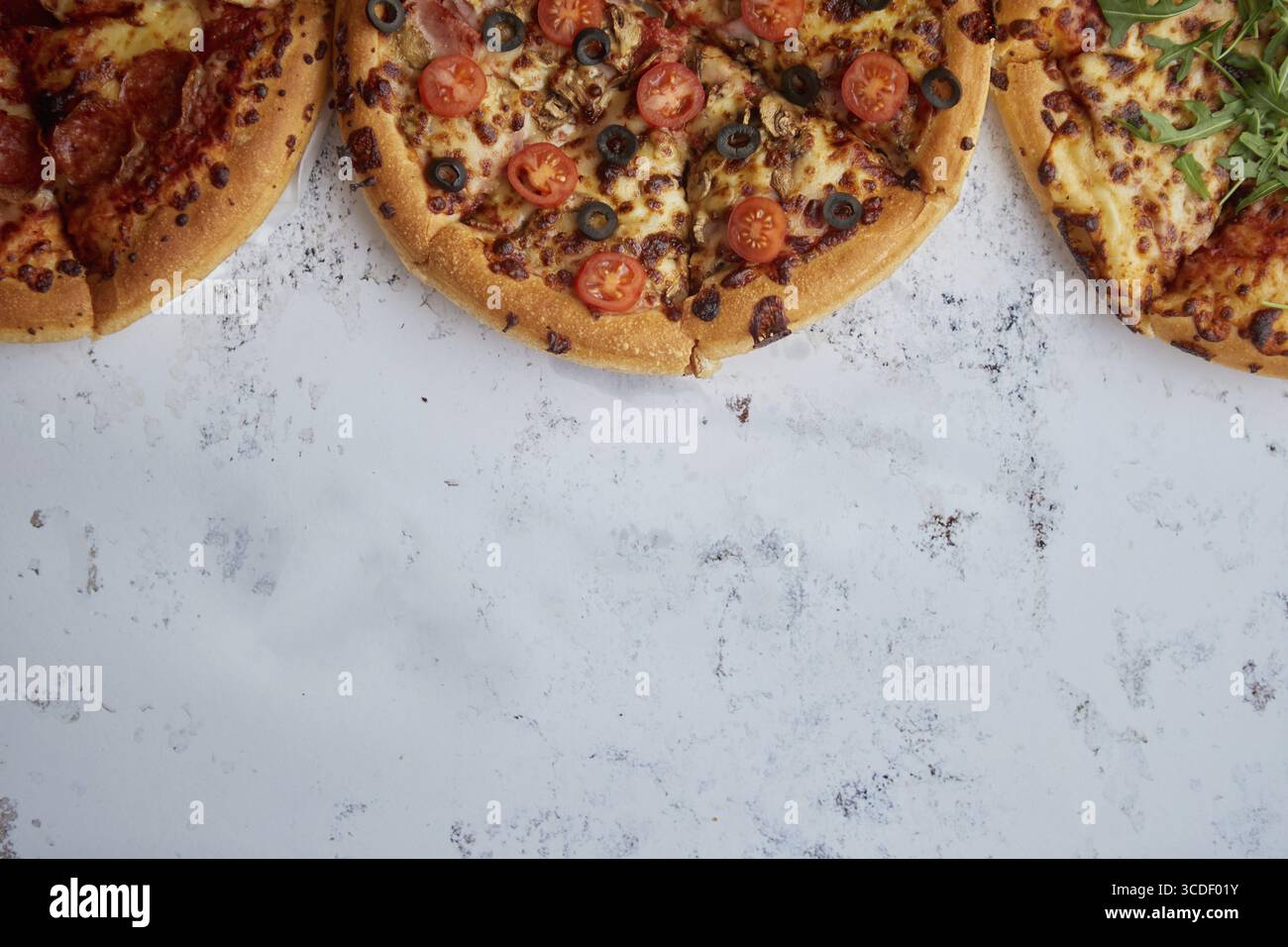 Trois sortes différentes de pizzas. Placé dans une rangée sur la table rouillée blanche. Vue de dessus avec un espace pour votre texte Banque D'Images