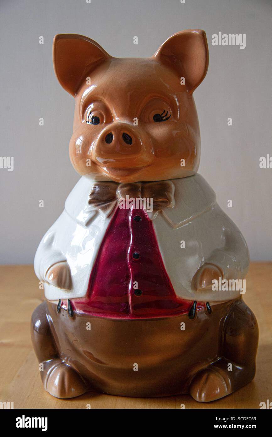 Image de nature morte d'un pot de stockage en porcelaine dans la forme comique d'un cochon habillé de vêtements humains Banque D'Images