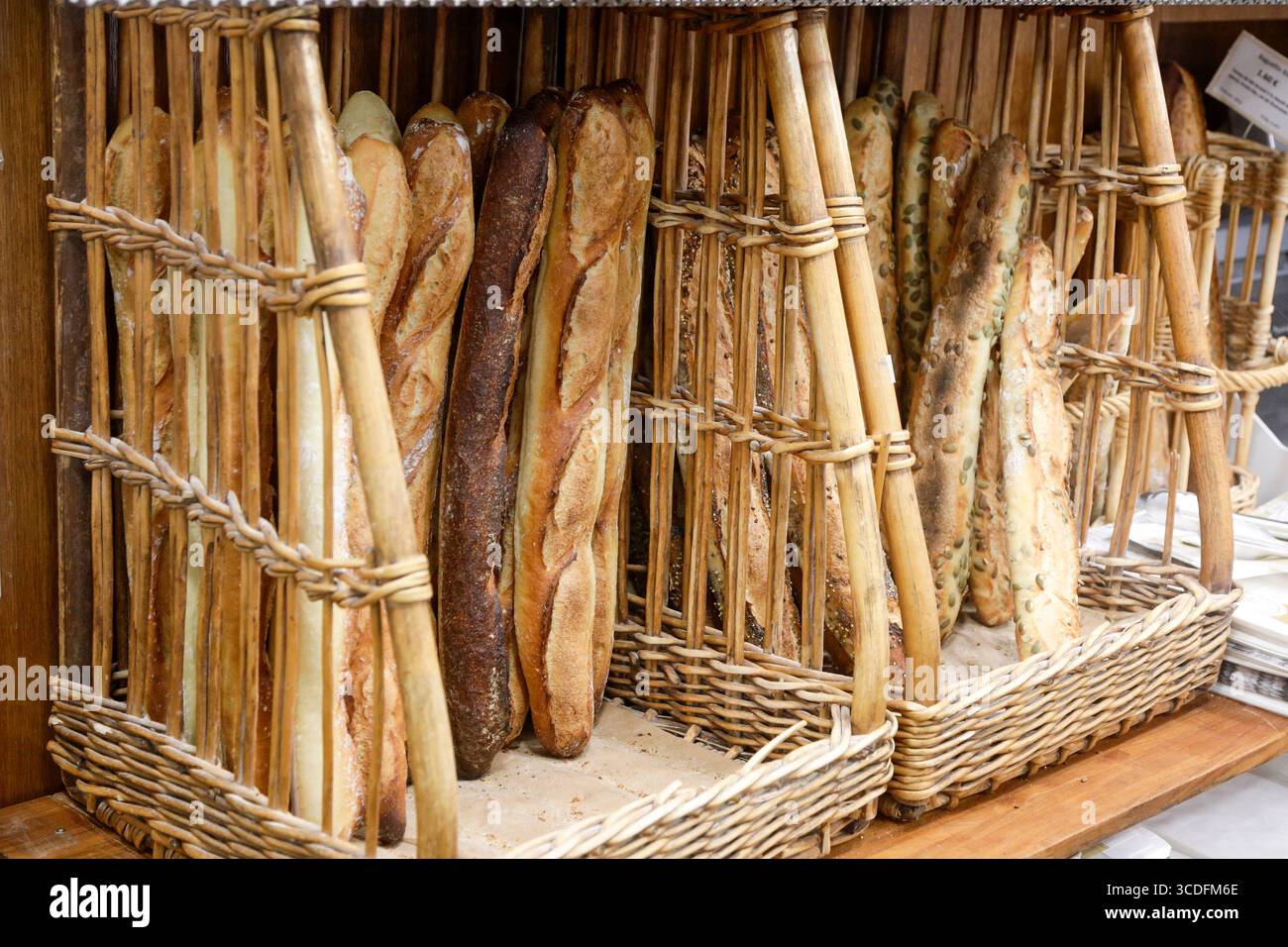 Paris, France. Baguettes fraîches debout dans des paniers dans une boulangerie locale dans le marché alimentaire du 18ème arrondissement. Banque D'Images