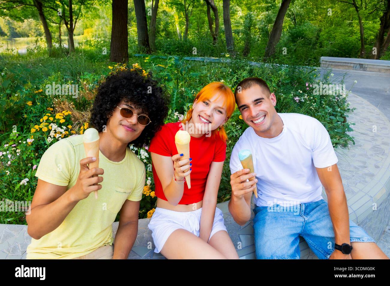 Trois amis dégustant des cônes de crème glacée dans un parc Banque D'Images