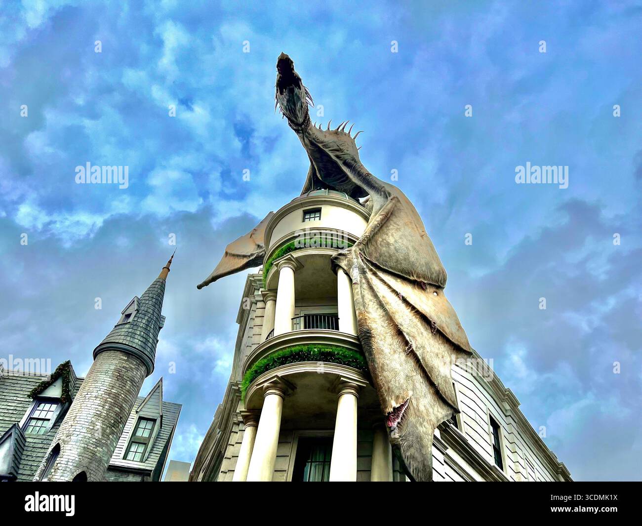 Dragon crachant le feu perché au sommet de Gringotts Bank sous le ciel nuageux dans le monde des sorciers de Harry Potter à Universal Studios à Orlando, en Floride. Banque D'Images