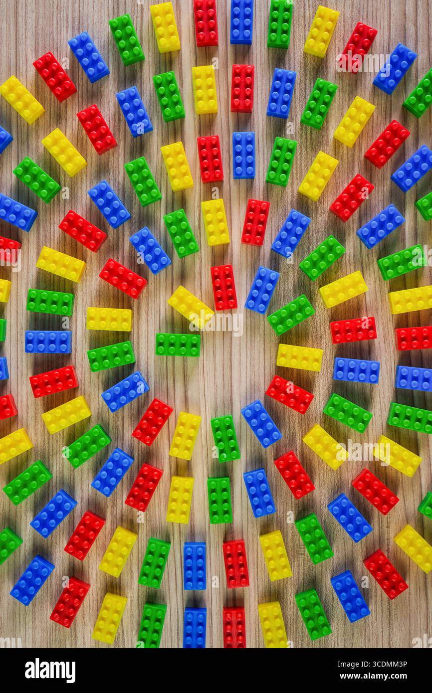 Blocs de construction en plastique coloré disposés en spirale sur une surface en bois. Banque D'Images