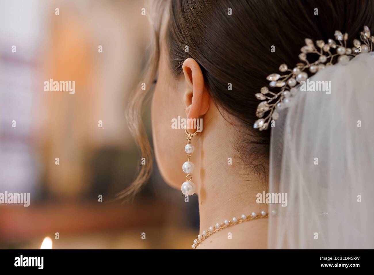 Superbe gros plan d'une mariée portant un peigne de cheveux de perles délicates et boucles d'oreilles avec un voile fluide, des bijoux en or, capturant deta de mariage romantique Banque D'Images