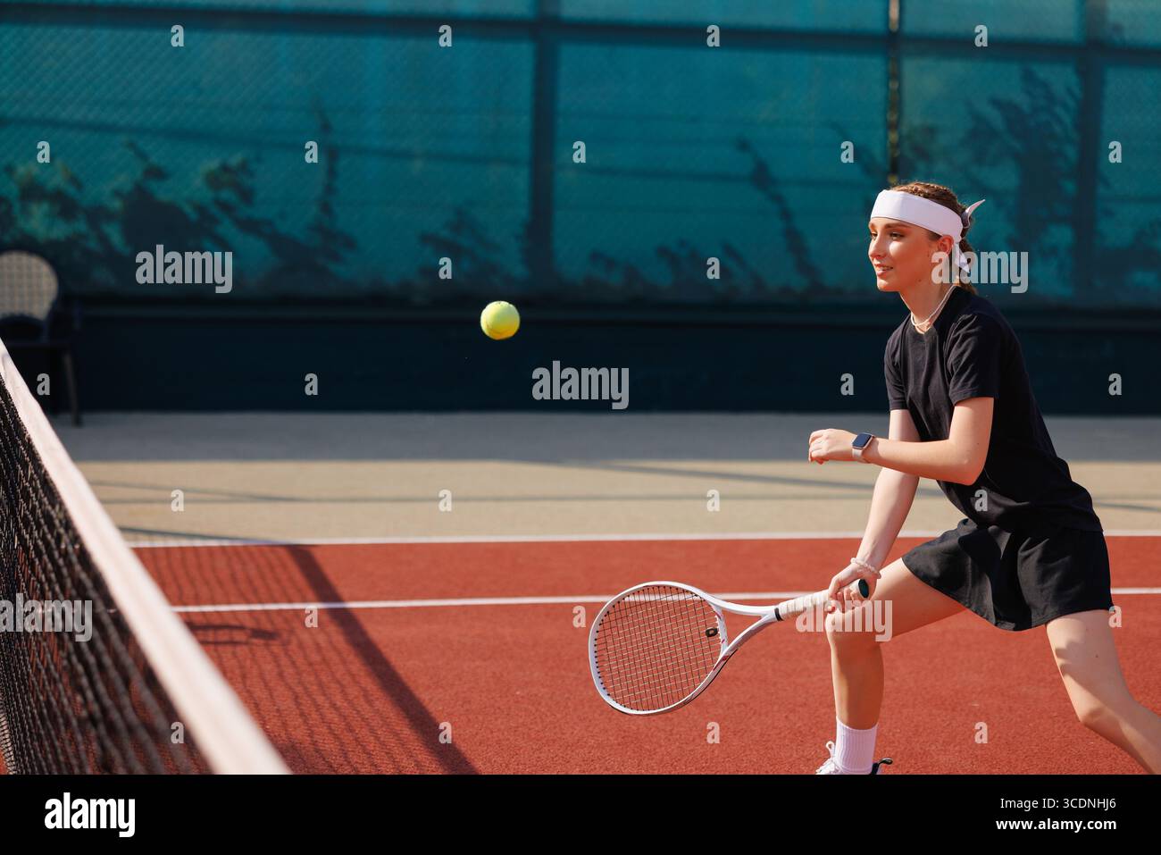 Fille concentrée en tenue noire pratiquant le tennis au filet, représentant le sport féminin, l'entraînement et l'entraînement actif Banque D'Images