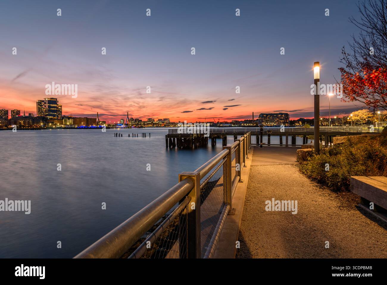 Sentier déserté de bord de port à East Boston au crépuscule en automne. Le front de mer du centre-ville de Boston est visible de loin. Banque D'Images