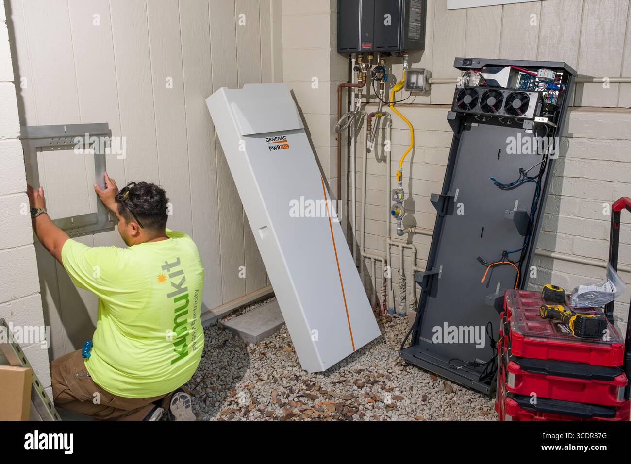 Jeune homme installant un support mural pour l'armoire de batterie Generac PWRcell lors d'une installation photovoltaïque résidentielle, Honolulu, Oahu, Hawaii, Etats-Unis Banque D'Images