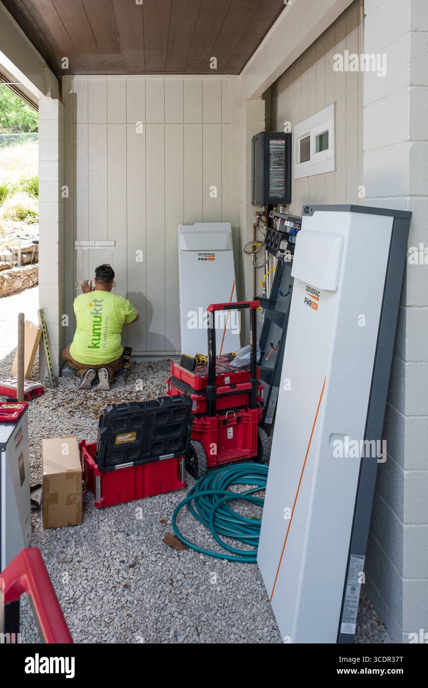 Jeune homme installant un support mural pour l'armoire de batterie Generac PWRcell lors d'une installation photovoltaïque résidentielle, Honolulu, Oahu, Hawaii, Etats-Unis Banque D'Images