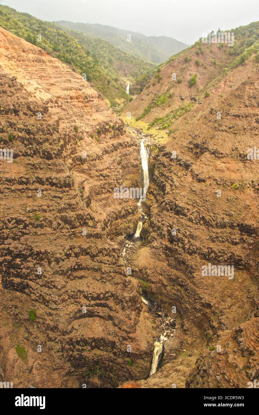 Chute d'eau à plusieurs niveaux creusée à travers la roche rouge de Waimea Canyon, souvent appelé le Grand Canyon du Pacifique. Banque D'Images