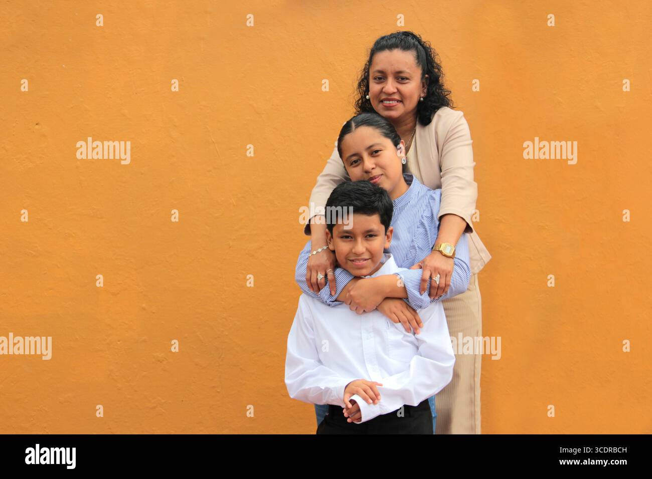 La mère, la fille et le fils latino-américains à la peau foncée montrent leur amour avec des câlins et célèbrent la fête des mères avec leur famille Banque D'Images La mère, la fille et le fils latino-américains à la peau foncée montrent leur amour avec des câlins et célèbrent la fête des mères avec leur famille Banque D'Images