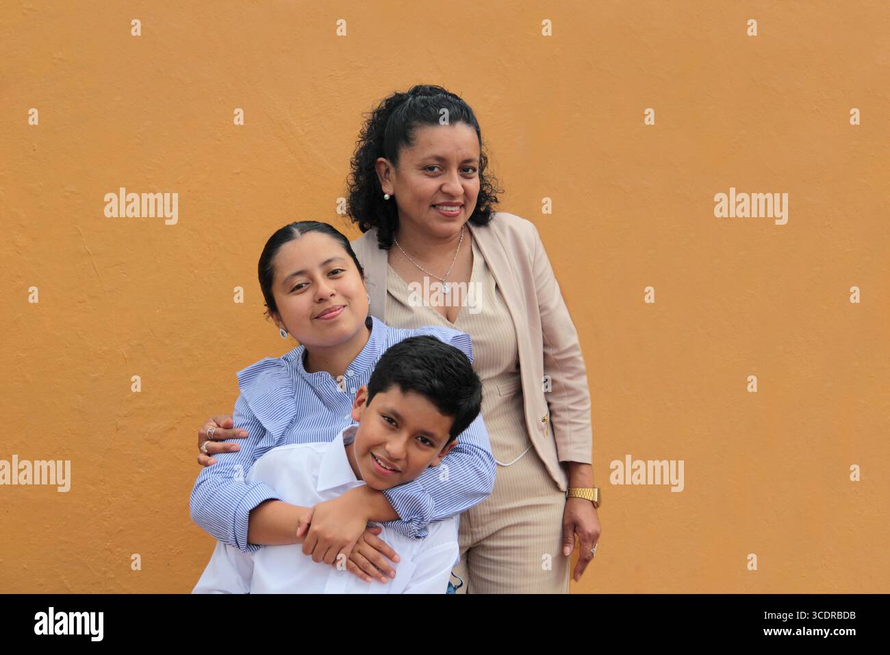 La mère, la fille et le fils latino-américains à la peau foncée montrent leur amour avec des câlins et célèbrent la fête des mères avec leur famille Banque D'Images La mère, la fille et le fils latino-américains à la peau foncée montrent leur amour avec des câlins et célèbrent la fête des mères avec leur famille Banque D'Images