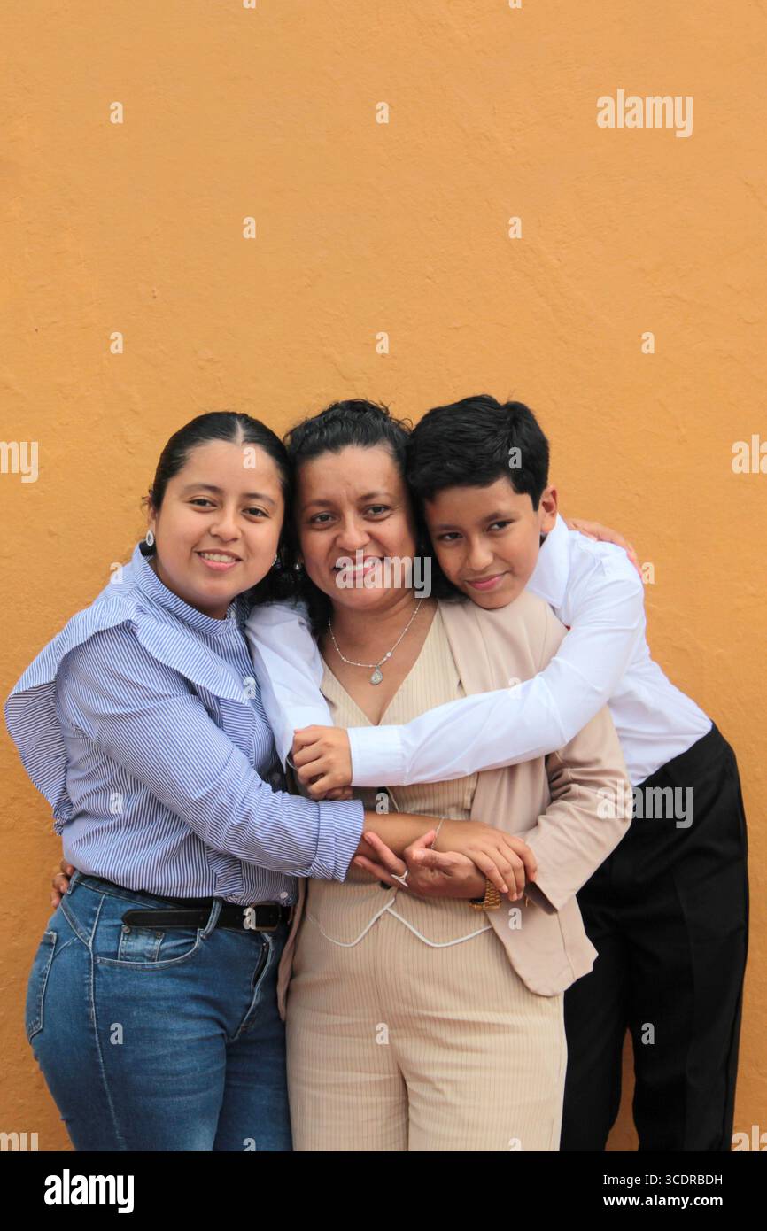 La mère, la fille et le fils latino-américains à la peau foncée montrent leur amour avec des câlins et célèbrent la fête des mères avec leur famille Banque D'Images La mère, la fille et le fils latino-américains à la peau foncée montrent leur amour avec des câlins et célèbrent la fête des mères avec leur famille Banque D'Images