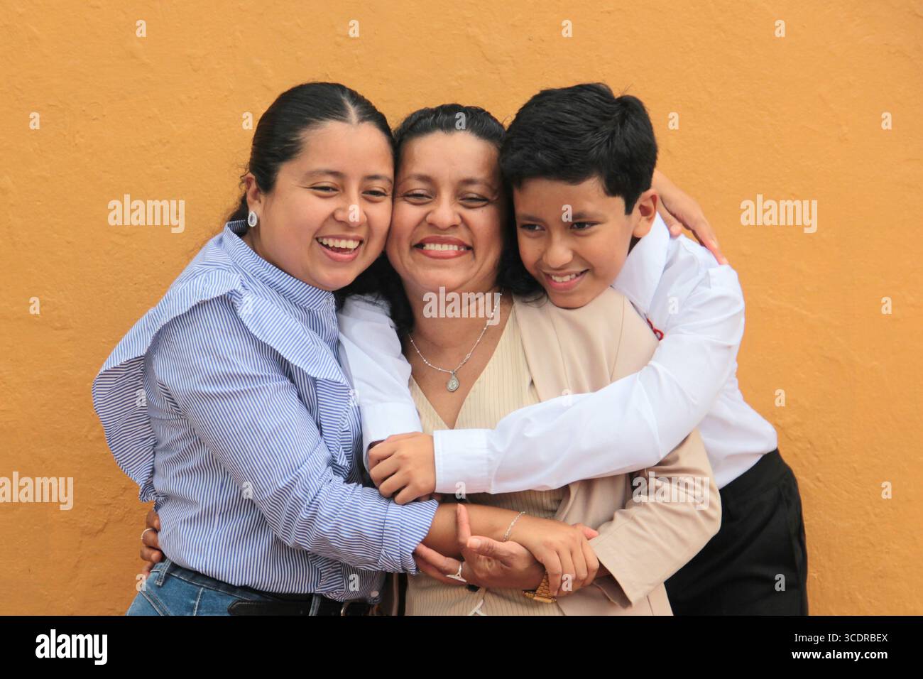 La mère, la fille et le fils latino-américains à la peau foncée montrent leur amour avec des câlins et célèbrent la fête des mères avec leur famille Banque D'Images La mère, la fille et le fils latino-américains à la peau foncée montrent leur amour avec des câlins et célèbrent la fête des mères avec leur famille Banque D'Images