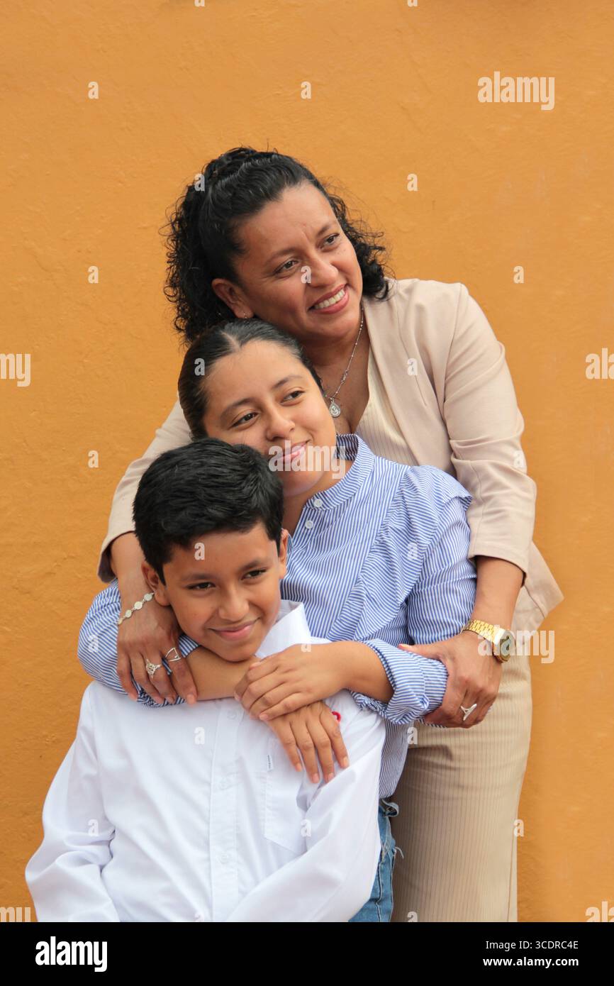 La mère, la fille et le fils latino-américains à la peau foncée montrent leur amour avec des câlins et célèbrent la fête des mères avec leur famille Banque D'Images La mère, la fille et le fils latino-américains à la peau foncée montrent leur amour avec des câlins et célèbrent la fête des mères avec leur famille Banque D'Images