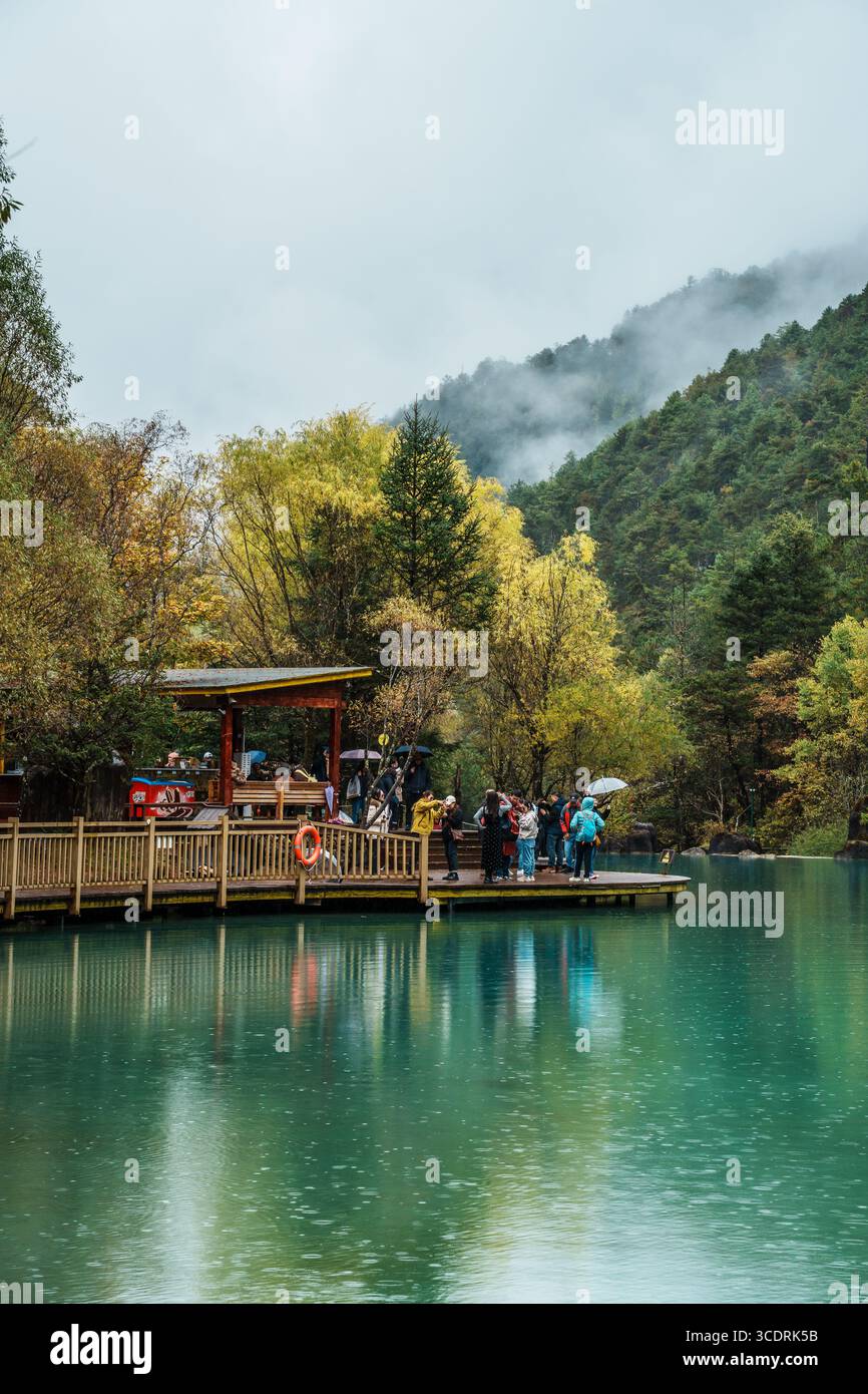 Lijiang, Chine - 24 octobre 2024 : les touristes se rassemblent sur une plate-forme d'observation en bois au-dessus des eaux turquoises, entourés d'arbres colorés dans Blue Moon Valley, L. Banque D'Images