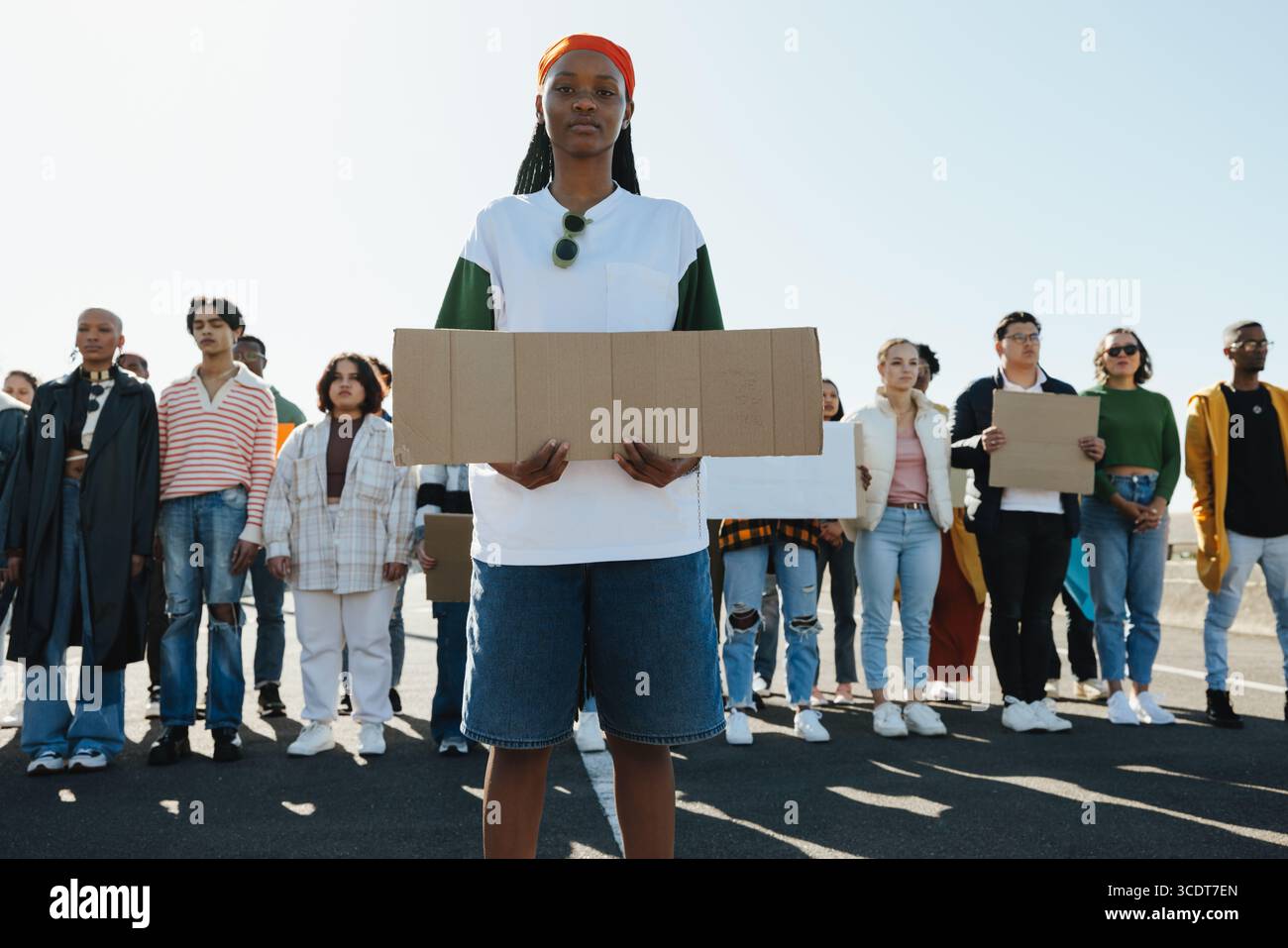 Grand groupe multiculturel de jeunes individus faisant preuve de solidarité et d'unité tout en tenant des pancartes vides dans une manifestation pacifique sous un clair Banque D'Images