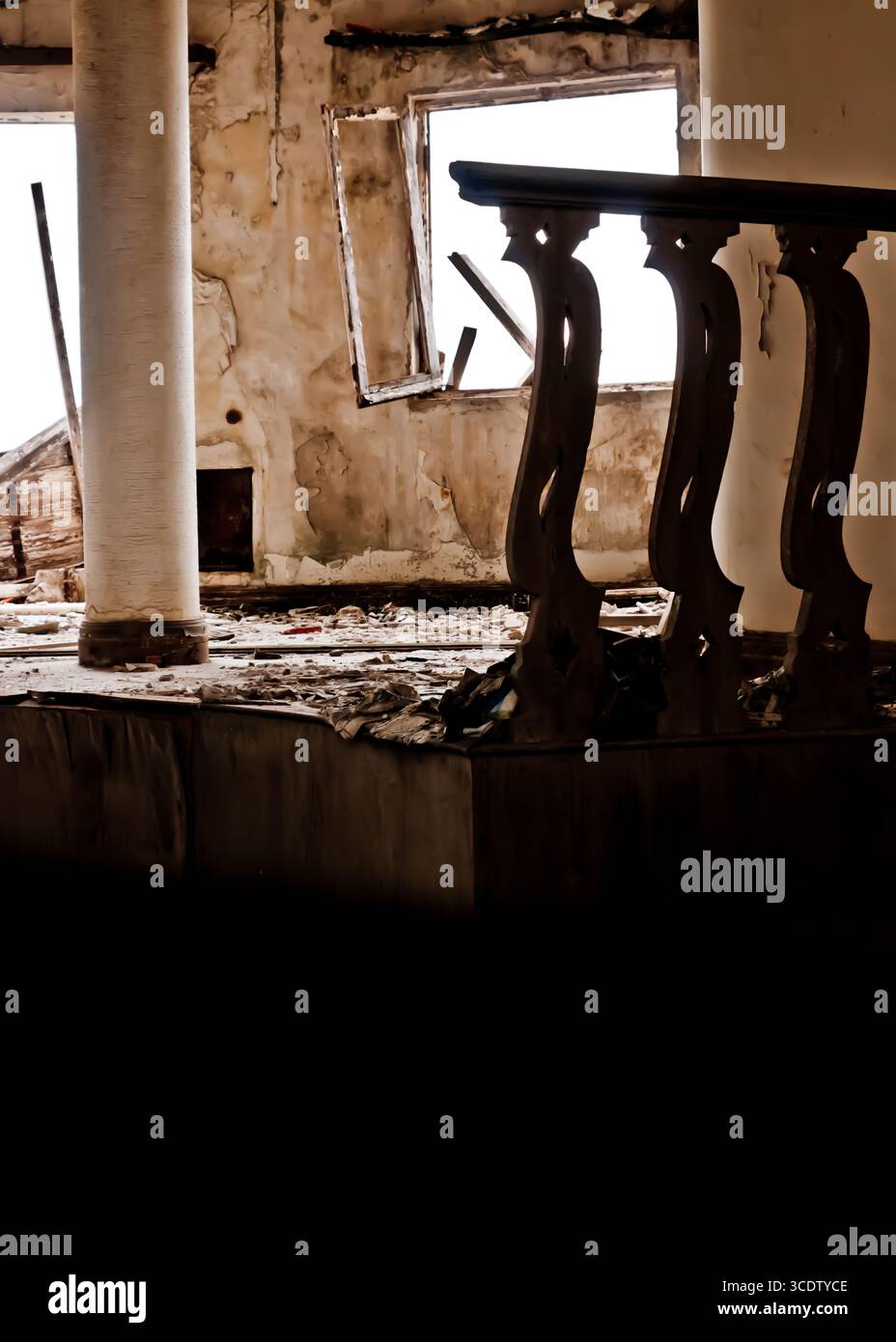 Une photo intérieure d'un bâtiment délabré, avec un pilier altéré, une balustrade décorative en bois et un cadre de fenêtre. Les murs montrent des signes de déc Banque D'Images
