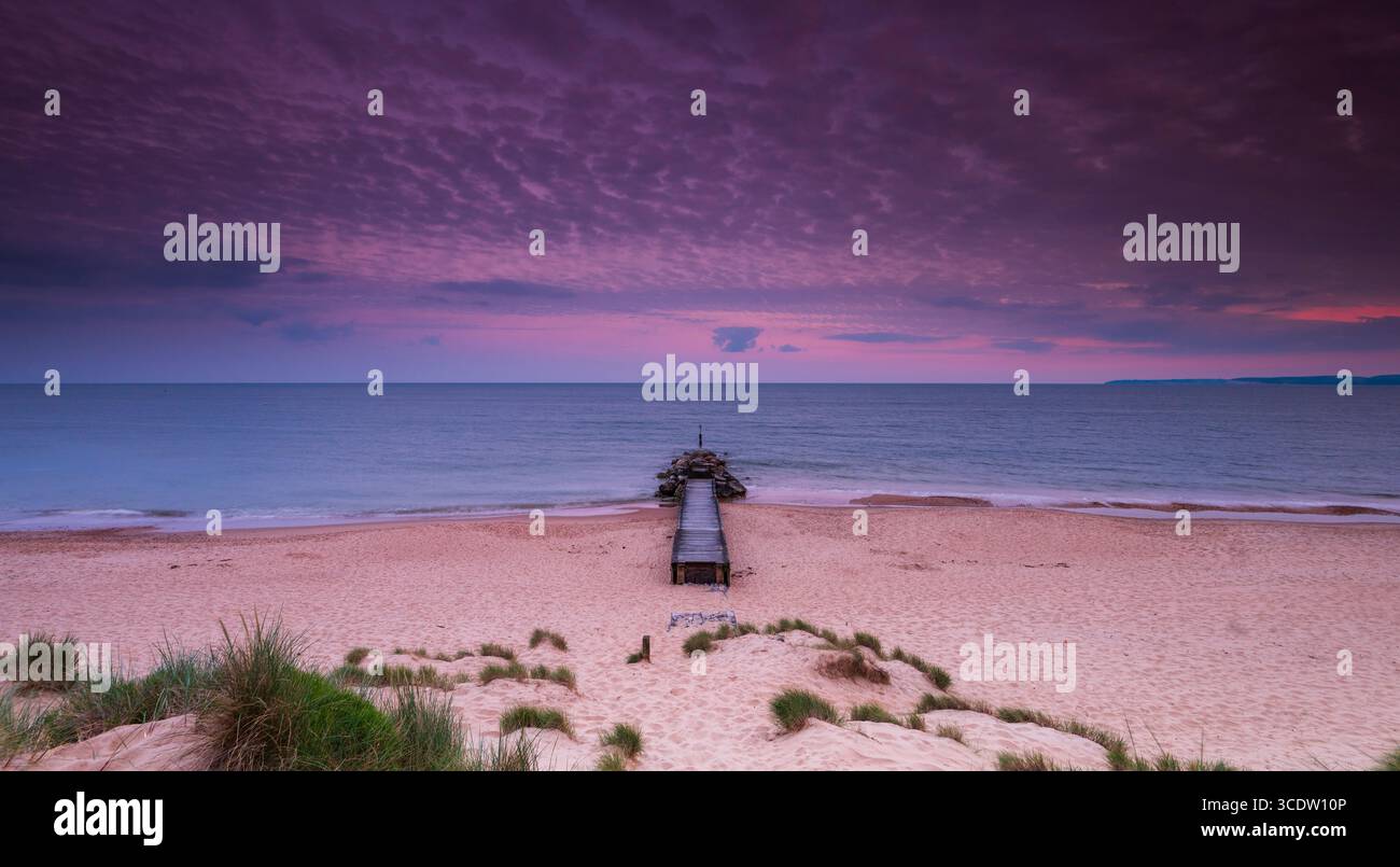 Eaux calmes à Southbourne plage illuminée par le soleil couchant au coucher du soleil Banque D'Images