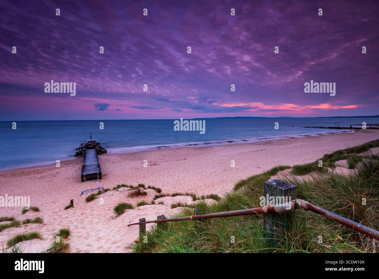 Eaux calmes à Southbourne plage illuminée par le soleil couchant au coucher du soleil Banque D'Images