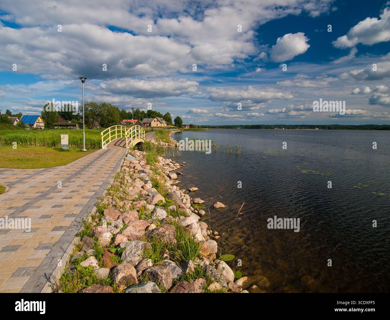 Juillet 2010, Võru, Estonie : promenade au bord du lac Tamula avec passerelle pavée, pont jaune et nuages d'été. Banque D'Images
