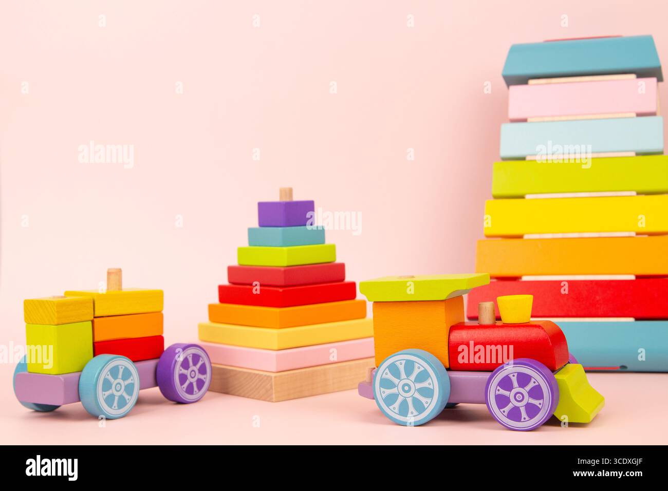Fond de jouets pour enfants. Jouets éducatifs et musicaux en bois Montessori pour enfants. Train en bois, xylophone, pyramide empilable sur fond rose. Avant Banque D'Images