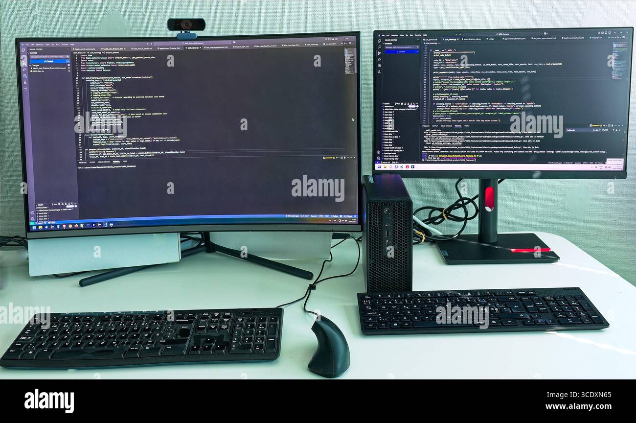 Dualmonitor authentique configuration de développement IA montrant le développement de code propriétaire réel et les processus de réglage fin de LLM dans un environnement professionnel Banque D'Images