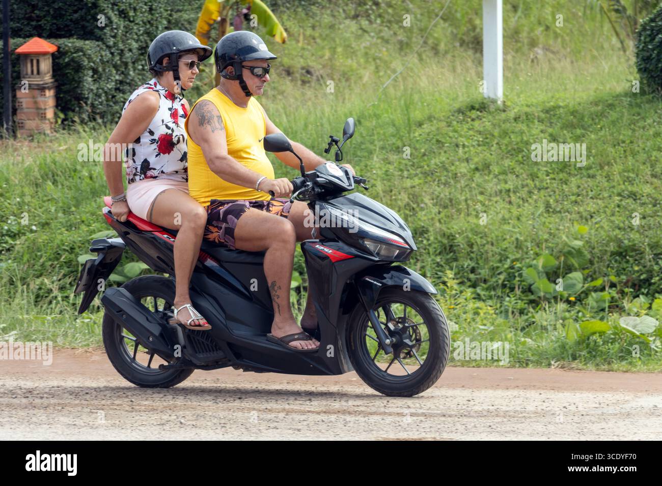 KOH LANTA, THAÏLANDE, DEC 01 2024, une paire de touristes conduisent une moto louée le long d'une route de campagne Banque D'Images