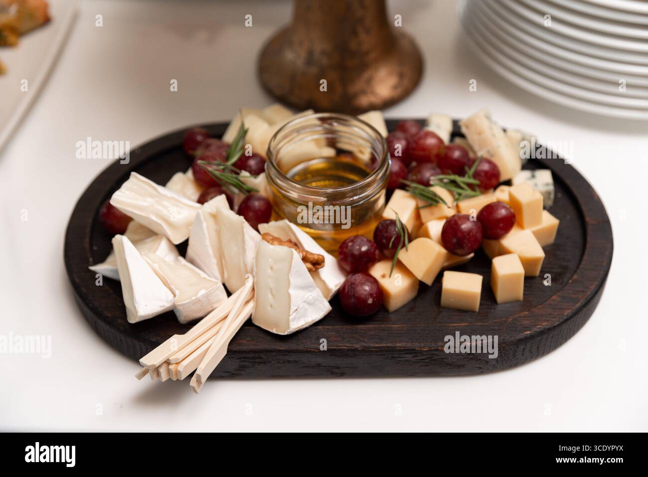 Un plateau magnifiquement arrangé avec une variété de fromages, raisins et miel, idéal pour les rassemblements. la combinaison de saveurs et de textures crée Banque D'Images