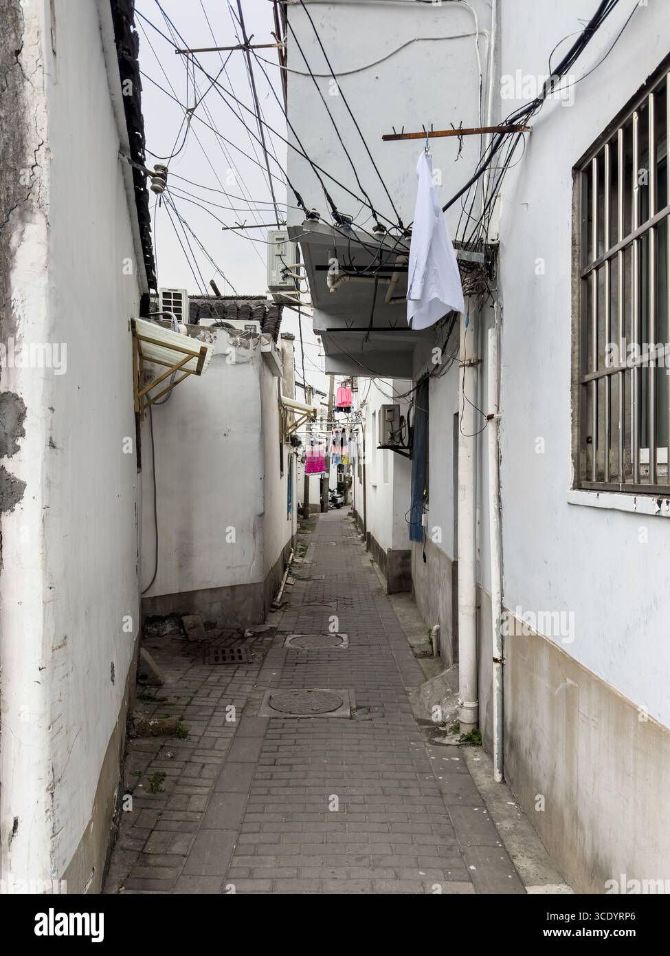 Suzhou, Chine, la blanchisserie pend au-dessus d'une ruelle étroite entre des murs blancs dans un quartier résidentiel traditionnel. Banque D'Images