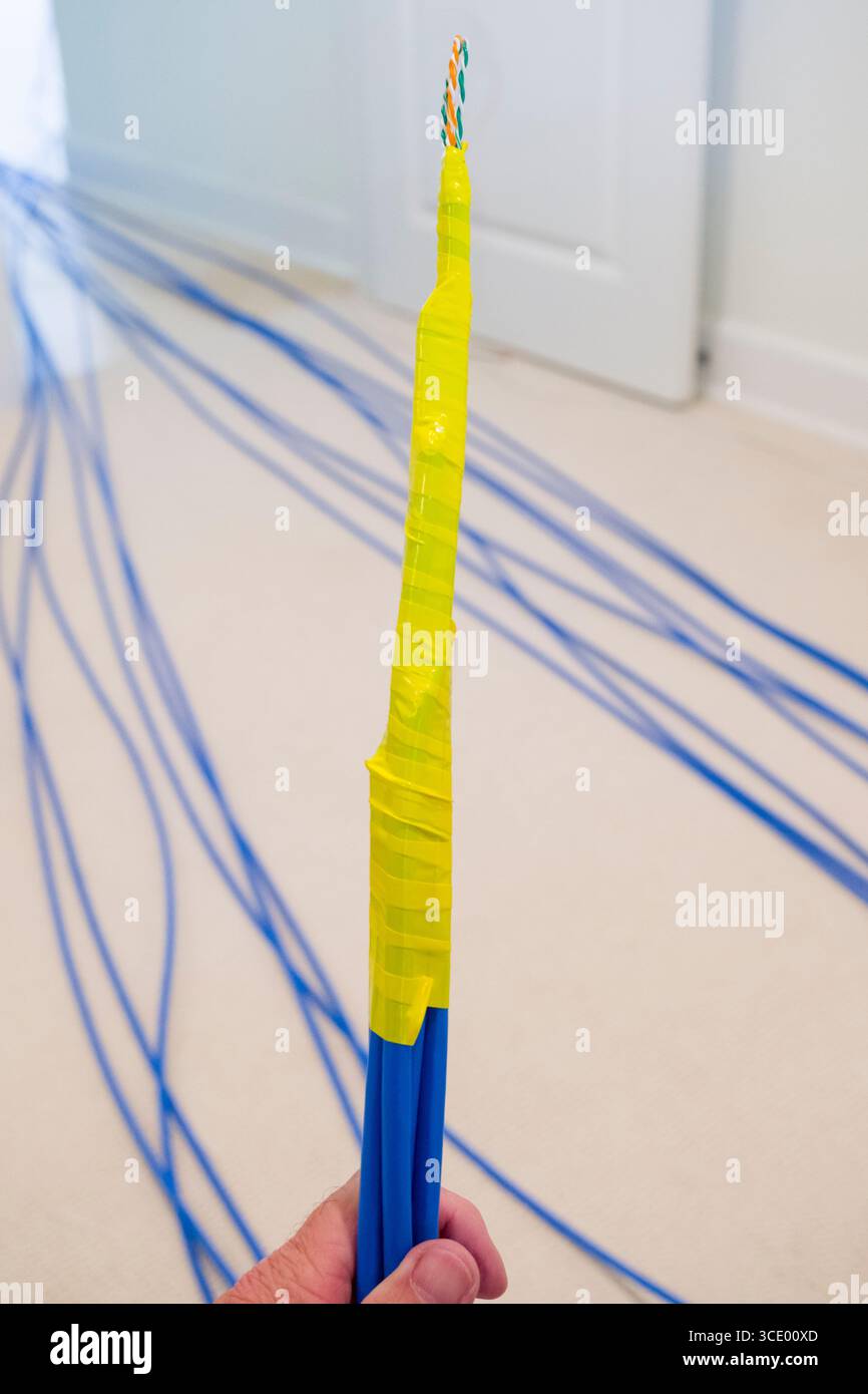 Ruban électrique jaune enroulé autour de plusieurs câbles ethernet Cat-6A bleus pour tirer les câbles à travers les murs intérieurs et le plafond, États-Unis Banque D'Images