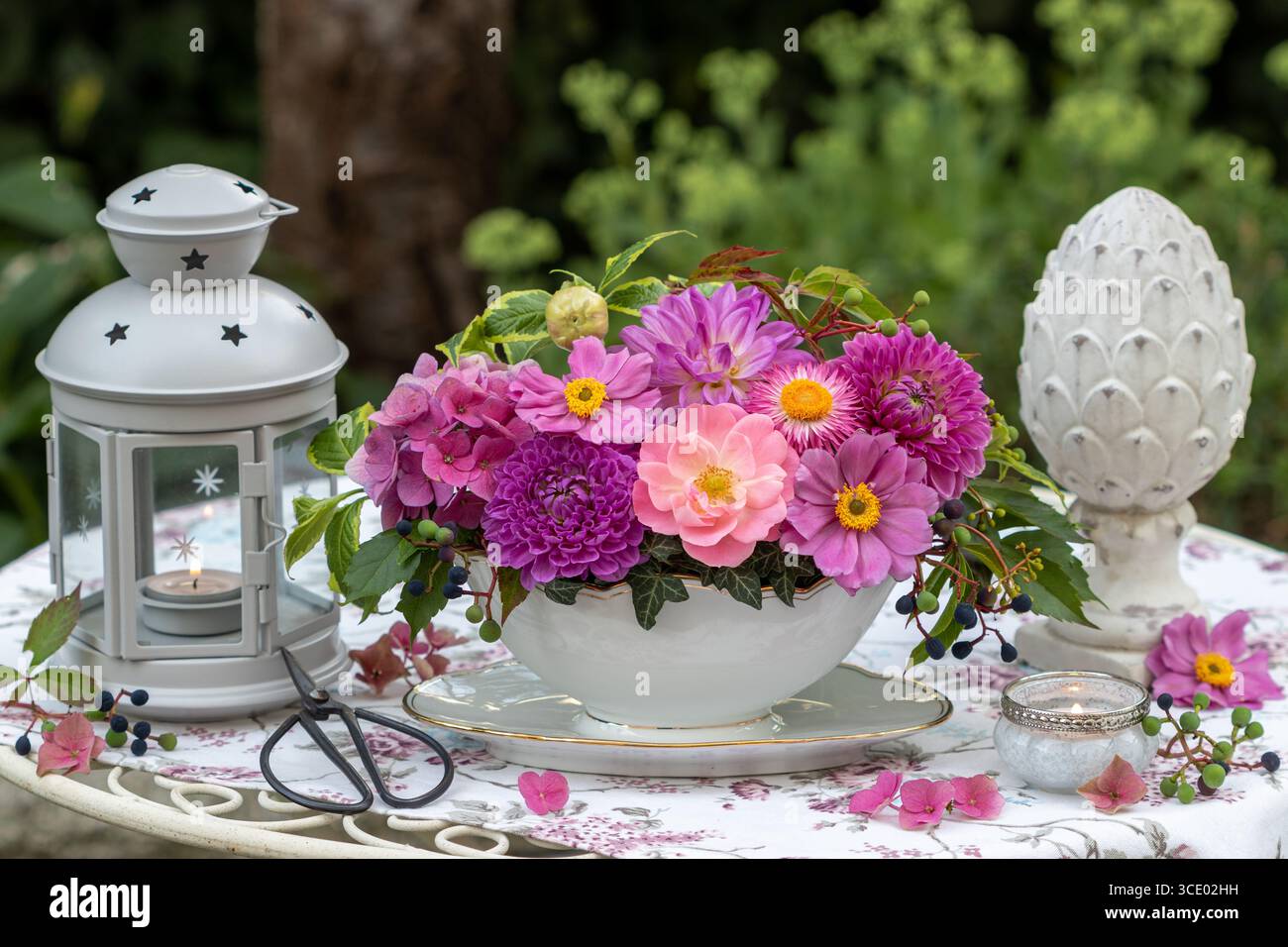 arrangement floral de rose rose rose, de dahlias, de fleurs d'hortensia et d'anémones japonaises dans un bateau à sauce et une lanterne dans le jardin Banque D'Images