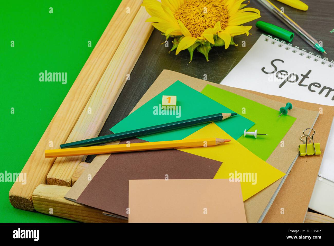 Concept de papeterie de retour à l'école avec tournesol, cahier et texte « septembre » sur fond de tableau noir, pose à plat, espace de copie Banque D'Images