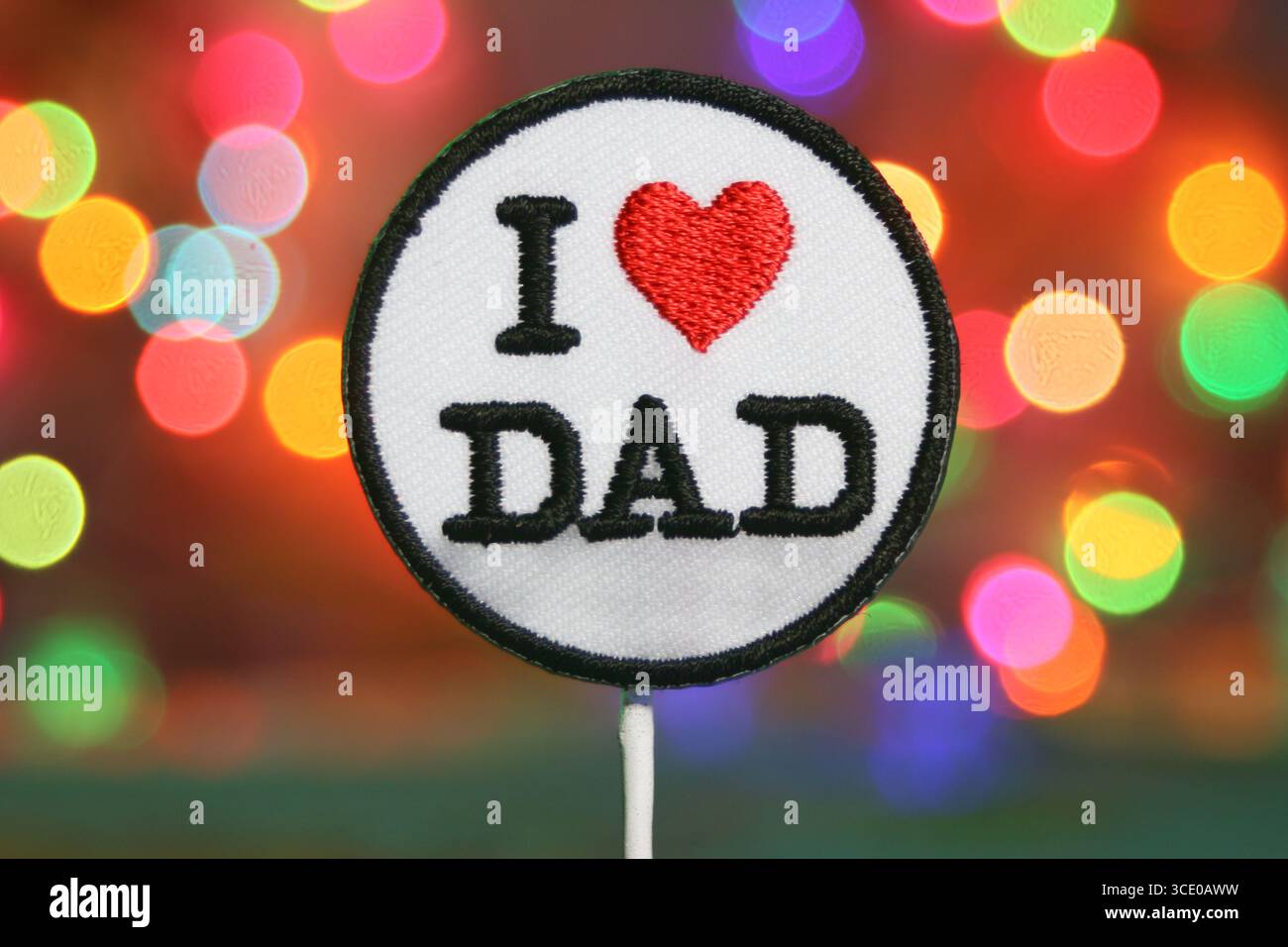 Badge brodé “ I LOVE DAD ” avec cœur sur des lumières bokeh colorées, idéal pour la fête des pères et les visuels de célébration. Banque D'Images